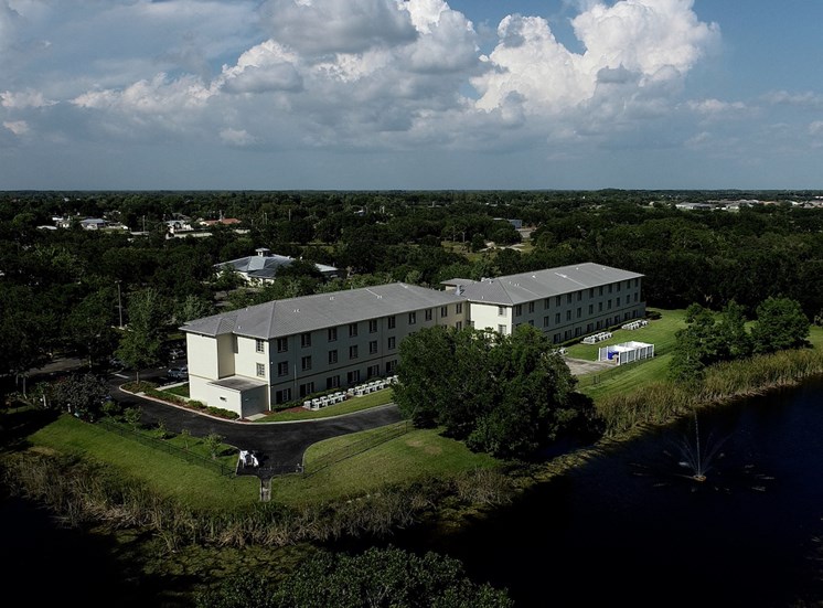 Villa Vincente Senior Apartments in For Myers, FL surrounded by trees beside water